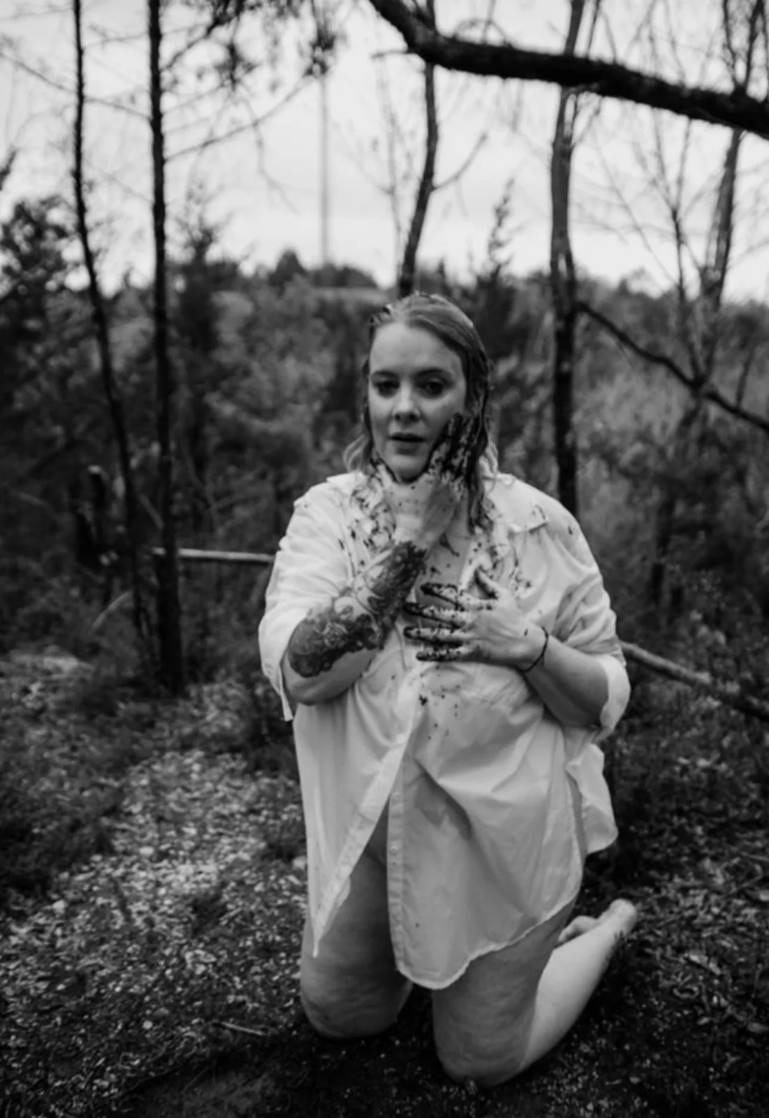 Lawrie kneeling in a forest, hands at her heart