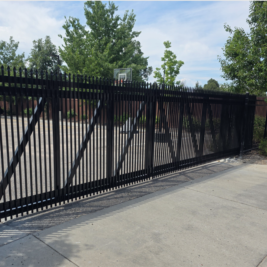 black metal fence with green trees and sky